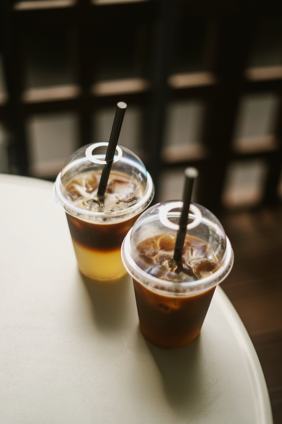 Two clear takeaway cups filled with iced coffee and fitted with dome lids